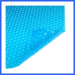 A close-up image of a blue bubble wrap material, showing a corner folded over. The bubbles are uniformly spaced across the surface, giving a textured appearance. The blue color contrasts with the white background. | AES - Pool Heating & Energy Efficient Products